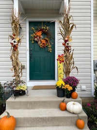 a front porch decorated for fall with pumpkins and corn